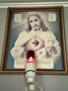A framed image of Jesus with a glowing red light underneath.